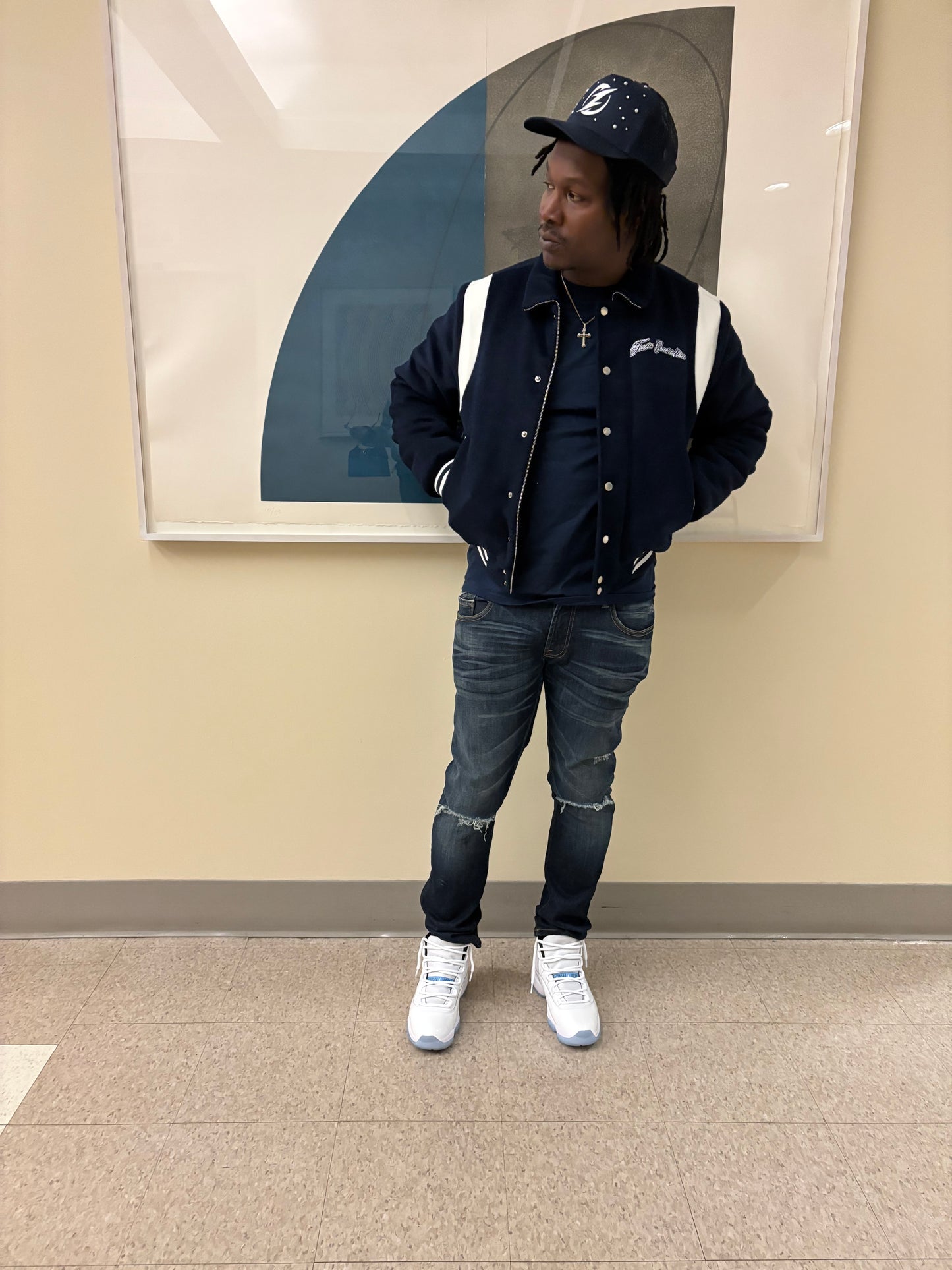 Person wearing a navy coat, jeans, and white sneakers standing in front of a mirror.