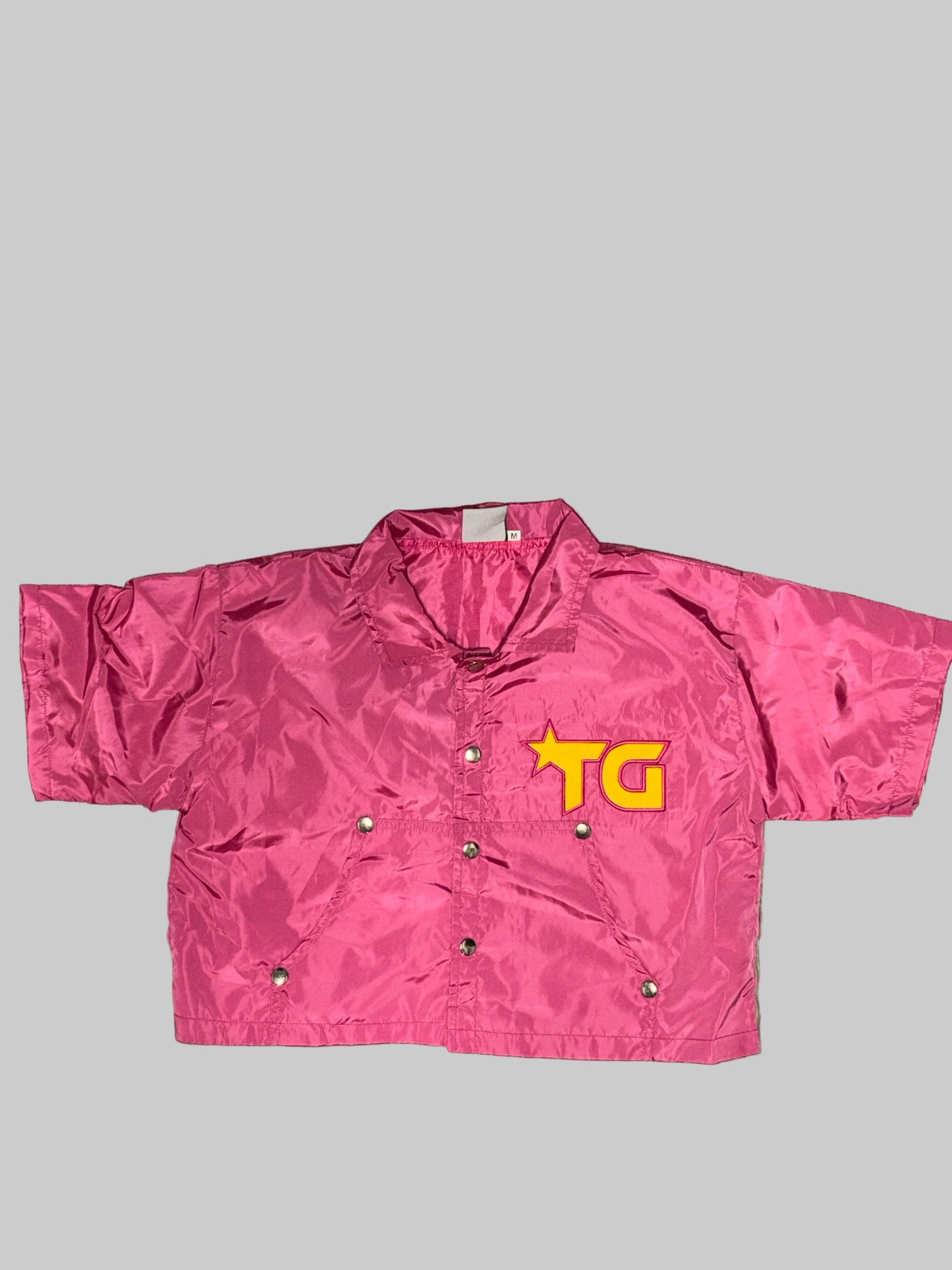 Pink snow pants with a yellow logo on a wooden floor