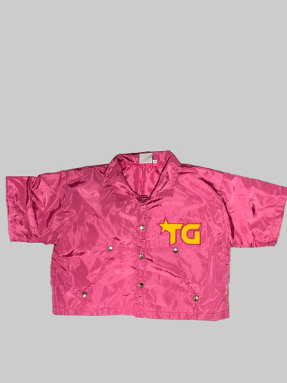 Pink snow pants with a yellow logo on a wooden floor